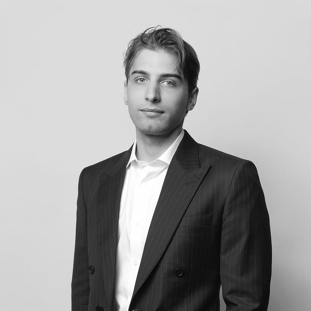 Pavlo Puzikov, a black and white studio portrait in a pinstripe suit.