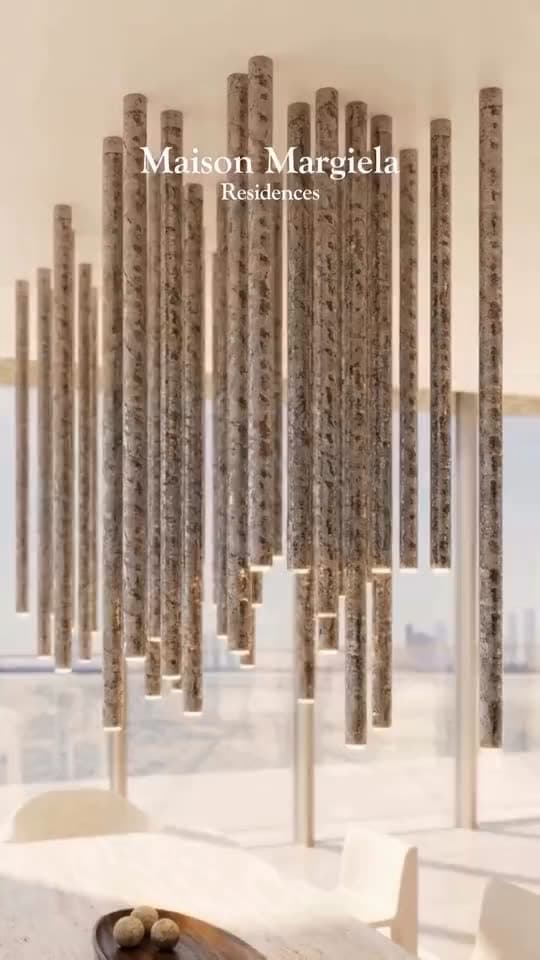 A suspended field of stone-clad columns over a dining table, the city beyond the glass.
