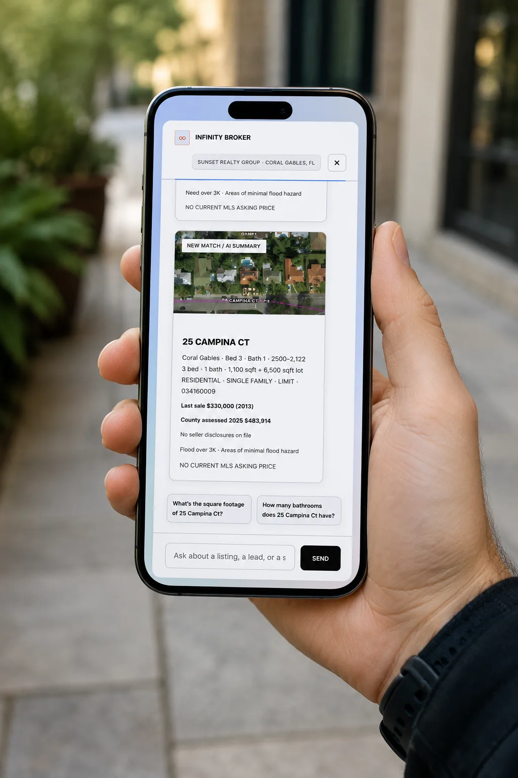 The Infinity Broker mobile chat held on a phone, showing a Coral Gables property card with real Miami-Dade aerial imagery and county record fields.