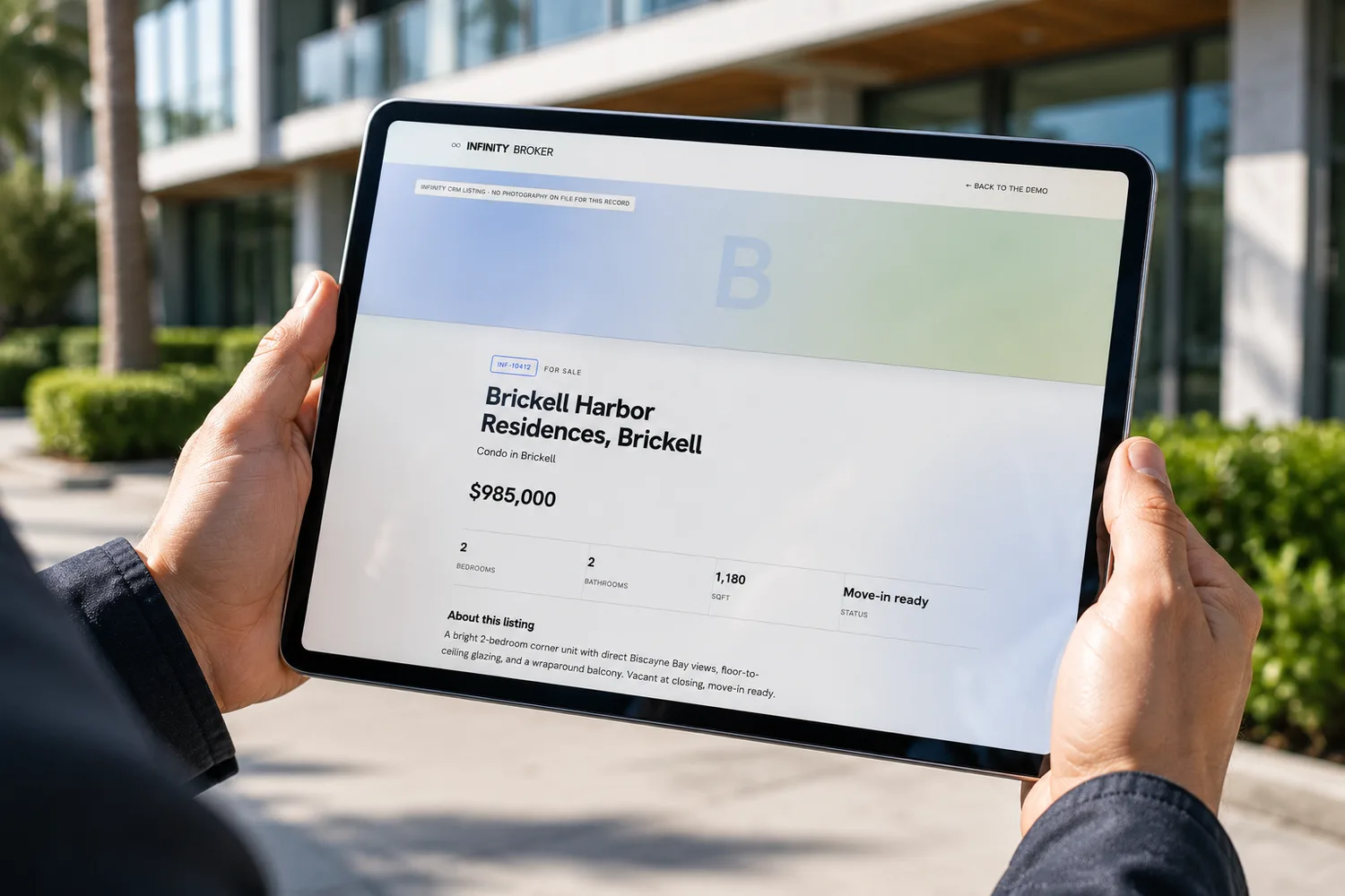 A per-listing page for a Brickell condo held on a tablet, with an honest 'no photography on file for this record' monogram band instead of stock imagery.