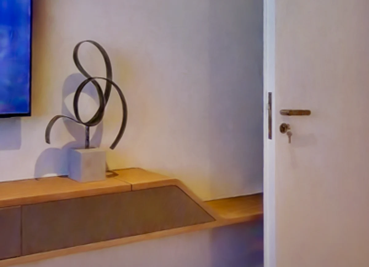 A scanned interior wall with a sculpture on a shelf, throwing a hard cast shadow up and to the left, the wall around it graded warm to cool.