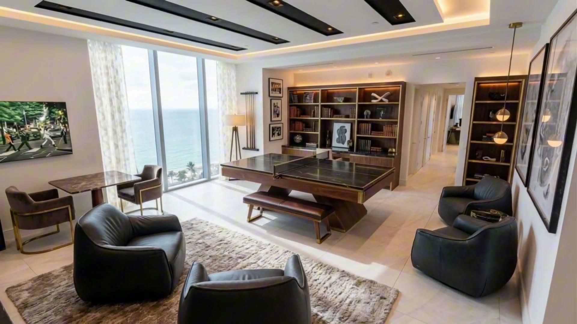 The same room restyled: walnut shelving lit from inside, a wood table-tennis table with a bench, leather lounge chairs and a shag rug.