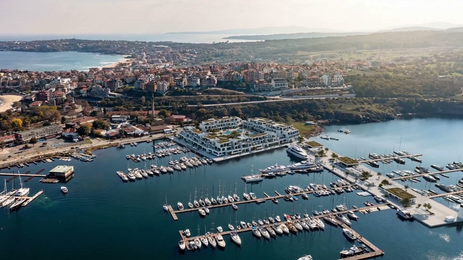 Aerial view of the same marina with the residences finished: white terraces, roof gardens and a full pontoon of yachts.