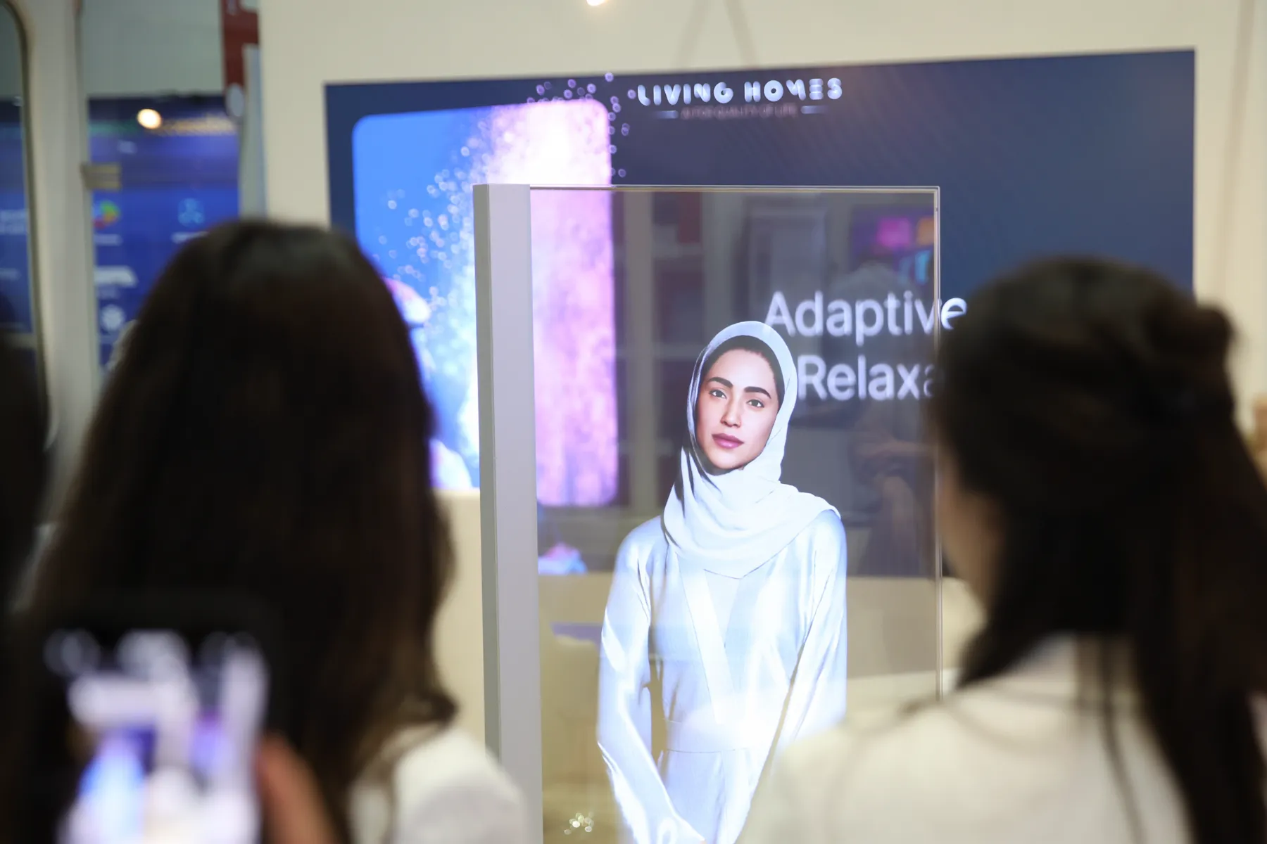 Two visitors watching a transparent mirror display running an Adaptive Relaxation demo on the stand.
